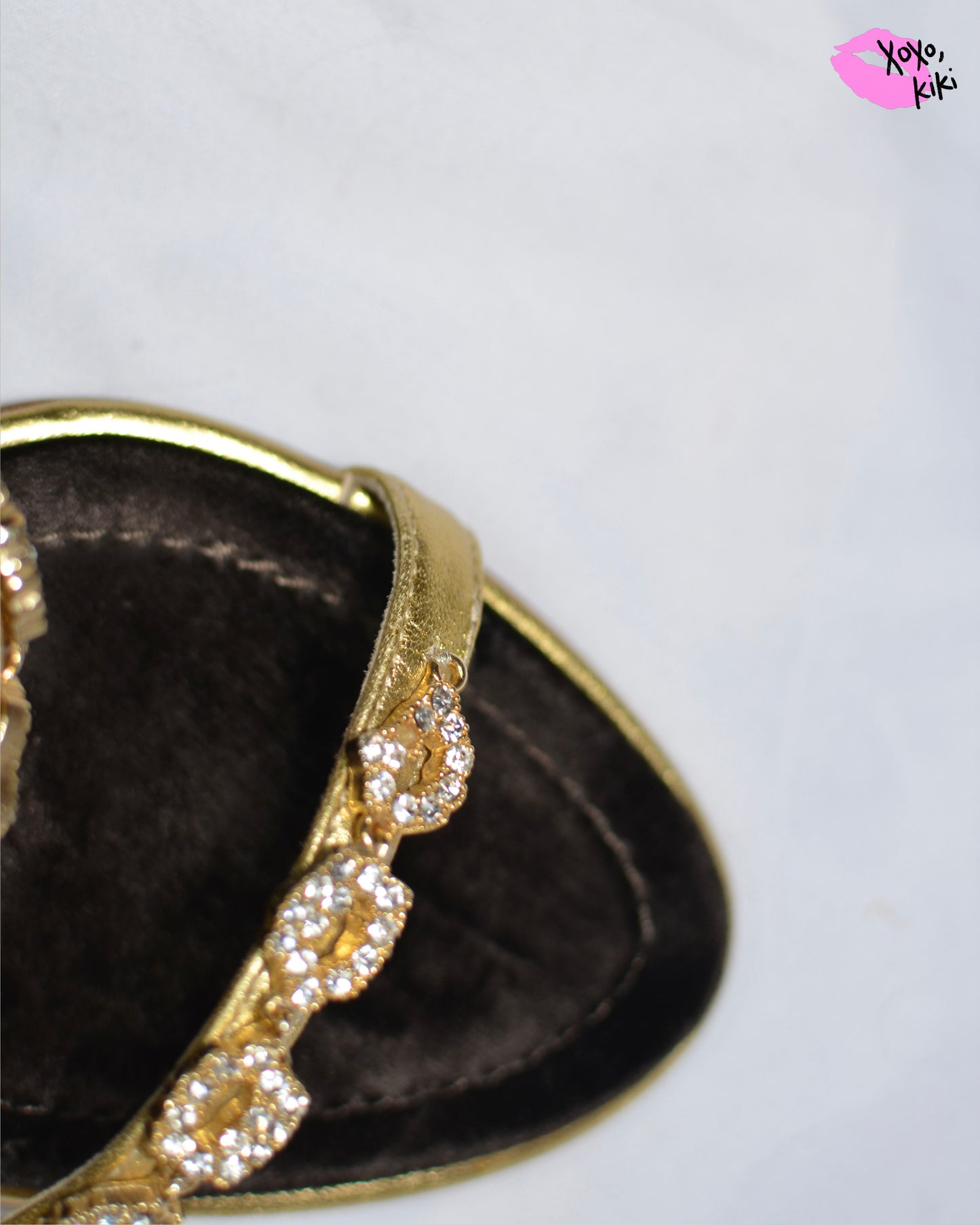 Close up of Gold high-heeled Giuseppe Zanotti sandals, close up on gold straps with embellishments and one small crystal missing from strap.