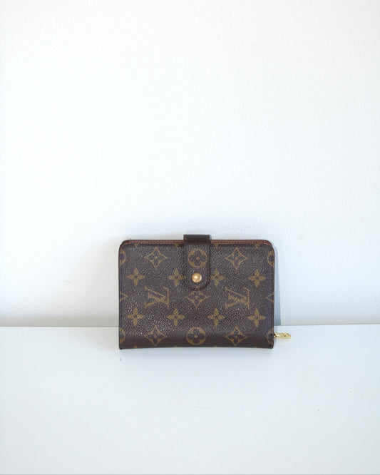 Louis Vuitton compact leather wallet inside compartments and zipper on a white background