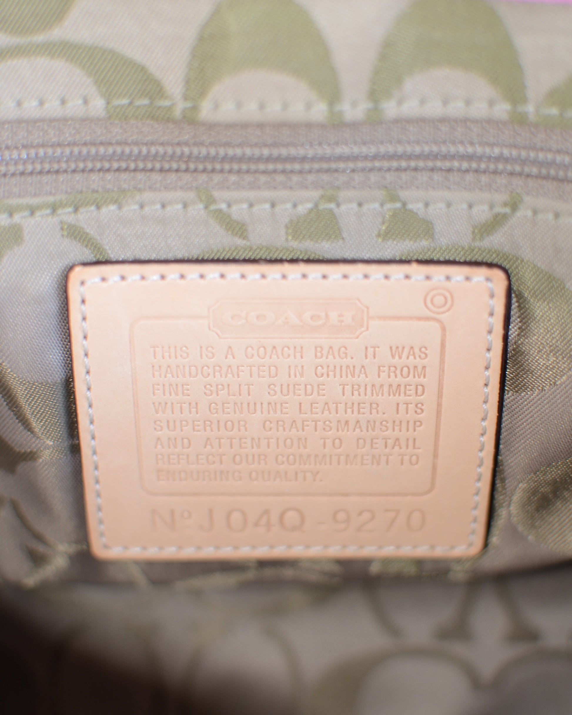 Close-up of coach tag and olive color monogram lining. Coach tag label reads Model No J04Q-9270