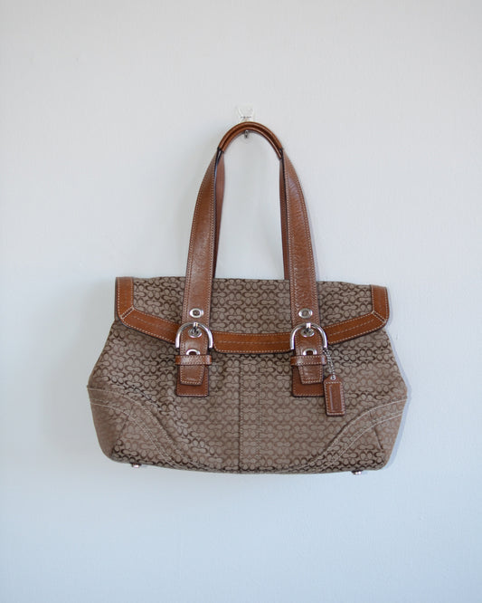 Coach brown textured handbag with leather straps on a light gray background